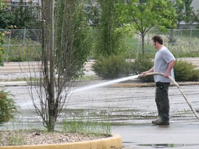 Several workers manned hoses and bobcats at the Syncrude Sport and Wellness Centre Wednesday to clear mud and debris from the parking lot leftover from Tuesday's major flood of the area. AMANDA RICHARDSON/TODAY STAFF