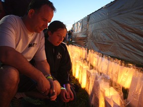 Joel Bergeron, left, pauses with his daughter Lexie to take a moment beside a luminary lit in honour of his late father Hygin, who died of cancer 13 years ago. Both hope and remembrance were themes at this year's Relay for Life in Timmins. Thousands of lit luminaries surrounded the O'Gorman High School track in honour of those who've battled and overcome cancer, and in memory of those who were not so fortunate.