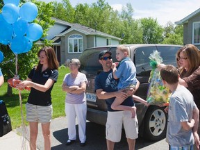 Joshua Viau is in his dad's arms as a Greater Sudbury Fire Department truck stops by his house. (Sebastien Perth/The Sudbury Star)