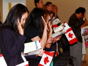 New Canadians take the oath of citizenship.