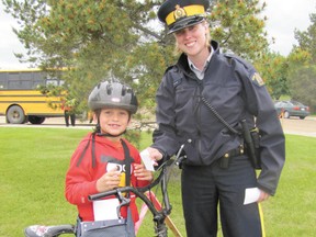 Mayerthorpe RCMP Const. Megan Olynek presents a gift certificate for a slurry to Kolbe Langdale, a Grade 1 Elmer Elson Elementary School student, on Monday, June 10, as a reward for wearing his bicycle helmet. The “positive tickets” are sponsored by Blue Heron Support Service Organization to encourage bicyclists to follow safe practices which will help them avoid brain injury.
