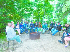 Campers assemble around a campfire.