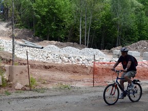 A cyclist rides past a sewer construction site at the north end of Harrison Park.