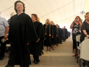 Confederation College graduates heading toward the stage for their diplomas as their family and friends look on. 
ALAN S. HALE/Daily Miner and News