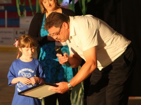 Michaela Hiebert/ R-G
Pictured (l-r): Kyla Hartman (age six, from Springfield Elementary School) receives a certificate from Lisa Armstrong (middle, North Peace Gymnastics Club Head Coach)and Bill Downing (DMI Mill Manager) at DMIís Million Minutes to Win It celebration on Thursday June, 6. Hartman was the winner gymnastic clubís Name That Place Contest. Hartmanís entry of the DMI Endurance Centre will be the official name of the new gymnastics club facility. As part of winning the contest, Hartman also won a  trip to the facility after it opens.