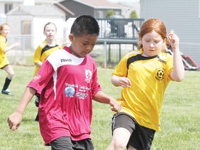 Wetaskiwin’s Glenville Bedua, left, dribbles the ball around Millet’s Abby Whittaker in U-10 soccer action at the Millet/Wetaskiwin Classic Soccer Tournament June 8 in Millet.