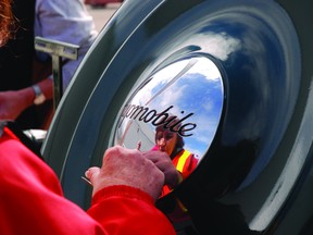 A volunteer cleans the hubcap of a vintage auto