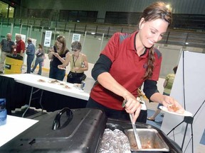 As guests savour sample servings in the background, volunteer Donna Powell prepares another plate of Madelyn's Diner buttertart-inspired pork tenderloin at the Pork Congress Wednesday. (SCOTT WISHART The Beacon Herald)