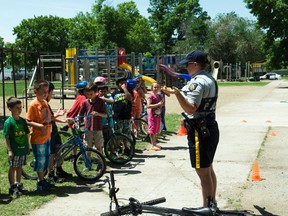 Const. Candace Harris demonstrates proper bicycle hand signals during a bicycle rodeo held at Fort la Reine School, Wednesday. She also taught students how to properly obey traffic signs while riding their bicycles. (ROBIN DUDGEON/PORTAGE DAILY GRAPHIC/QMI AGENCY)