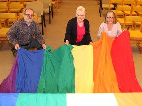 Richard Rainville, left, executive director of the Access Network, Rev. Dawn Vaneyk, of St. Peter's United Church in Sudbury, ON. and Paddy Buchanan, chair of St. Peter's church council, place a cloth on the alter that represents the rainbow colours of the Pride flag. The church is celebrating its designation as an Affirming Ministry. JOHN LAPPA/THE SUDBURY STAR/QMI AGENCY