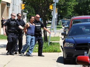 Sarnia police escort a handcuffed man to a squad car Wednesday afternoon on Wellington Street. Police say officers were called to a residence in the 300 block and arrested a 42-year-old man for assault with a weapon and aggravated assault in the stabbing of a 24-year-old man. The victim was transported to hospital and underwent surgery for multiple stab wounds. BLAIR TATE/THE OBSERVER/QMI AGENCY