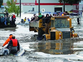 Evacuees are removed en masse via dump trucks, bucket tractors and boats after a flash flood in High River, Alta. on Thursday, June 20, 2013. The Highwood River running through High River was flooding extremely, prompting a town wide evacuation. Lyle Aspinall/Calgary Sun/QMI Agency