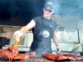Jon Harding bastes a rack of ribs at the Railroad Ribs booth at the Blues and Ribfest on Friday. (SCOTT WISHART, The Beacon Herald)