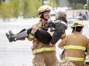 A rescued woman is carried by a firefighter out of a flood zone in High River on Thursday. The Highwood River running through High River was flooding extremely, prompting a town wide evacuation. Lyle Aspinall/Calgary Sun/QMI Agency