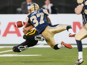 A Hamilton Tiger-Cats receiver gets hit so hard the ball goes flying out during Thursday night’s game against the Bombers. (STAN BEHAL/TORONTO SUN)