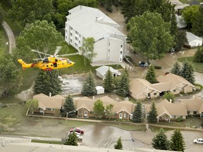 A search-and-rescue helicopter flies low over a flooded High River, Alta. on Friday, June 21, 2013. Massive flood waters throughout southern Alberta have heavily affected many thousands of residents. Lyle Aspinall/QMI Agency