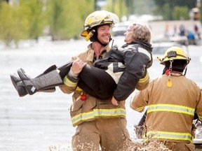 Shawn Wiebe, of the Nanton fire department, carries a rescued woman out of a flood zone in High River, Alta. on Thursday, June 20, 2013. The Highwood River running through High River was flooding extremely, prompting a town wide evacuation. (Lyle Aspinall/QMI AGENCY)
