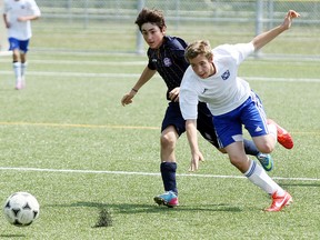 North Bay Select's Dylan Bond, right, gets tripped up chasing a loose ball with North Scarborough Soccer Club's Paul Akouris Sunday at Steve Omischl Sports Field Complex. The Selects won 3-0 and have yet to lose a game in five league matches.