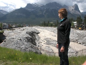 Colleen Vukadinovic looks downstream from Elk Run Boulevard at Cougar Creek and her heavily damaged Grotto Road home in the distance on the left on Sunday, June 23, 2013. Dave Husdal/ Special to Canmore Leader