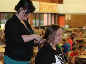 Bobbie Hutchinson cutting off 10 inches of Gina Chapleau's hair for the Locks of Love as the rest of the student body watched.