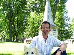 Steven Heighton and his dog Isla sit by the monument in Skeleton Park that formed the focus of one of the short stories in his book, The Dead Are More Visible, which was nominated for a Trillium Book Award.
