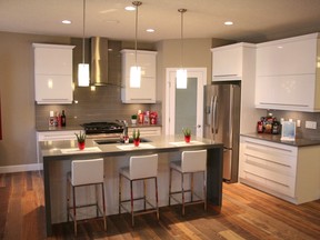 The kitchen features two banks of glossy white European-style cabinets, a grey quartz countertop and backsplash. (Supplied photo)