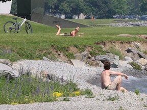 A couple of sun bathers enjoy the hot weather and Breakwater Park on Monday.
Ian MacAlpine The Whig-Standard