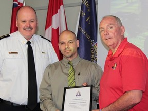 Timmins Police Chief John Gauthier, left, and Police Services Board Chair Tom Laughren, right, presented Detective Constable Rolly Giroux with a formal commendation Tuesday for his outstanding police work. (Photo distortion caused by computer screen display, our apologies)