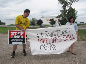 Zak Nicholls and Vanessa Gray hold up a banner outside the Enbridge site in Sarnia during a small rally Tuesday in support of activists who last Thursday took over a pipeline pumping station north of Hamilton. The activists hope to prevent construction on Enbridge's Line 9 project. (The Observer)