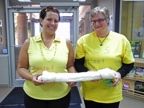 Secret Off-Leash Society (SOS) spokeswomen Michelle Dacyk (left) and Sandra Ross hold up their giant dog bone after making a presentation at a City of Grande Prairie council meeting on Monday. The organization is fighting for more off-leash dog areas and better dog park maintenance to keep the community clean and safe. (Elizabeth McSheffrey /Daily Herald-Tribune)