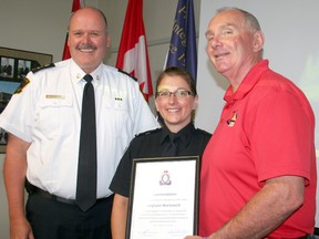 Leighann Workewich, a 911 team leader with the dispatch unit at the Timmins Police Service, is presented with a commendation from the police service for her role in assisting a man who was lost in the bush and fearful that he was being tracked by a bear. The commendation was presented to her by Timmins Police Chief John Gauthier, left, and Timmins Mayor Tom Laughren.