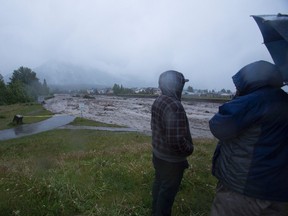Canmore residents look on as Cougar Creek rages towards the Trans-Canada Highway on Thursday morning, June 20, 2013. Justin Parsons/ Canmore Leader/ QMI Agency