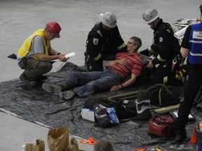 Two members of a mine rescue team compete in the first aid event while a competition judge (in the yellow vest) looks on. - Caitlin Kehoe, Reporter/Examiner