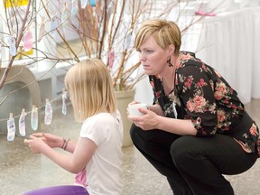 Veya Carter-Bidewell admiring the newborn socks of her siblings, Kalyb and Karys. Beside her is mom Mikle Carter a board member on Tiny Hands of Hope. (Courtesy Charlie Healey Photography)