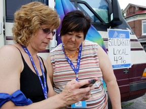 OPSEU Local 496 treasurer Pam Schmidt, left, uses her phone to show president Cheryl Whiteman social media updates on the local's labour dispute with Hastings County at a "strike station" outside county headquarters in Belleville Thursday. The parties will meet Tuesday with a mediator.