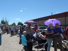 People scrambled for umbrellas and hats to stave off the scorching sun while standing in line at the Tom Hornecker Recreation Centre in Nanton on June 27, waiting to be processed for flood relief funds.
