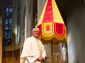 Most Rev. Douglas Crosby, bishop of Hamilton Diocese, poses next to an “ombrellino” that is now displayed in the sanctuary of the Cathedral Basilica of Christ the King. The umbrella-like standard is bestowed by a pope as a personal recognition that he has designated a church a minor basilica. (Photo courtesy of Mike Perron)