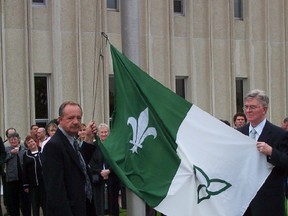 Michel Dupuis, left, and Gaetan Gervais, raise the franco-Ontarian flag they helped create in 1975 at a ceremony in Sudbury in 2011. (file photo)