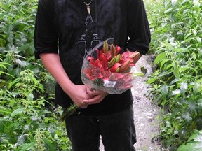 Jason Butler brings a  bouquet of lillies to the banks of the Grand River in memory of his friend Brent Brading-Searles. Brading-Searles' body was found Thursday in the river by an OPP dive team. (Expositor Photo)