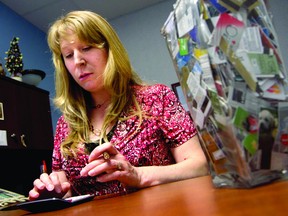 Betsy Elliott, a financial fitness professional at the Employment and Education Centre, crunches numbers. Next to her is a jar of cut-up credit cards she has collected from clients over the years (THOMAS LEE/The Recorder and Times).