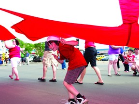 A member of the parade enjoys the shade of his group’s flag during the Canada Day parade on Franklin Avenue two summers ago. Today file photo