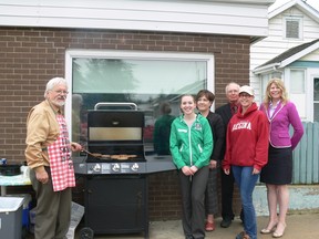 Jim Taylor flips burgers at the TSN Law, Habitat for Humanity barbecue on June 26.  (From left) lawyer Jim Taylor, student at law Loree Gillert, lawyer Darcy Neufeld, lawyer Ron Saretzky, volunteer co-chair and secretary Marla Walton and volunteer coordinator Shannon Rusk.