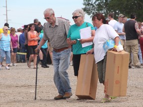 KEVIN RUSHWORTH HIGH RIVER TIMES/QMI AGENCY. At left to right, Gordon Williams, Krista Williams and Gerry Michaelsen carry their flood assistance supplies away from the welcome centre after long lines on Saturday June 29 at the High River rodeo grounds. Residents of northwest neighbourhoods returned home on Saturday to assess the damage done to their homes.