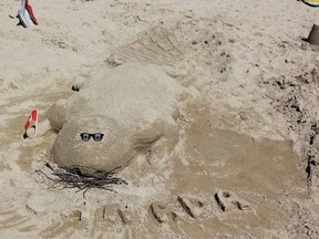 The lifeguards built a beaver statue for their sandcastle.