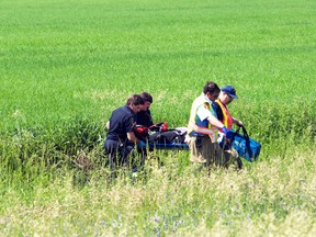 Emergency crews transport the occupant of a single vehicle accident to an ambulance, Tuesday. The driver lost control of a vehicle on Highway 16 south of Macdonald and it stopped in a farmer's field. She was transported to hospital with non-life threatening injuries. (ROBIN DUDGEON/PORTAGE DAILY GRAPHIC/QMI AGENCY)