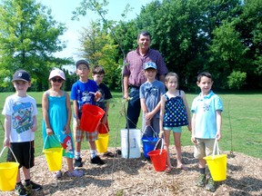 All ready to water new trees at Bobier are children from the Dutton Child Care Centre, left, Santino Pocheco, Olivia Corneil, Dylan Barrett, Ayden Gore, Kitt Carruthers, Kaitlyn Gore and Robbie McEachren. Joining them is Elgin County Warden Cameron McWilliam, standing behind.