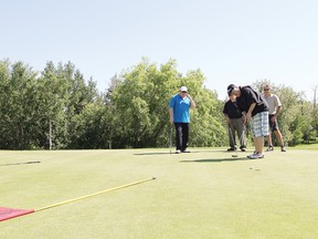 Jay Stiles sinks his putt at the ninth hole while teammates Wayne Shaw, left, Hugh Denham, and Len Deblois watch on during the 5th Annual Barry Prefontaine Memorial Golf Tournament June 28.