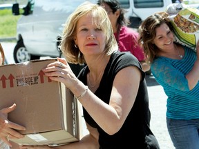 Laureen Harper, wife of Prime Minister Stephen Harper, helps unload the cavalcade of 15 vehicles loaded with supplies for the Morley emergency centre, June 26.