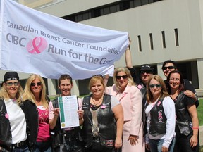 Cancer survivor Stephanie Koett along with fellow Iron Sirens, displays the proclamation signed by Mayor Marianne Matichuk during the flag raising ceremony at Tom Davies Square.