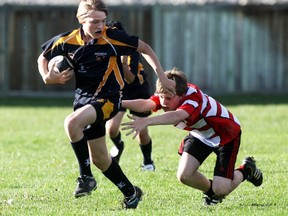 Bow Valley Bears U-13 player Graham Cockwill scampers out of harm’s way of the extended arms of a Calgary Saints player as the Bear won 50-30, June 25.